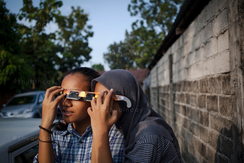 Dua anak perempuan melihat peristiwa gerhana matahari total melalui kaca mata yang telah disediakan di Sekolah Alam Minangkabau, Kota Padang, Sumatera Barat, Rabu (09 Maret 2016).
